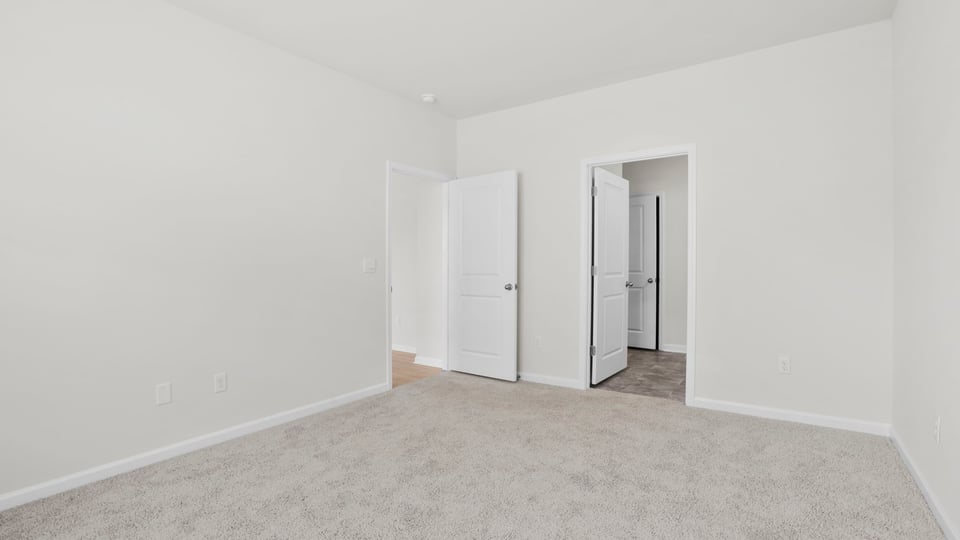 Primary bedroom with carpet and window.