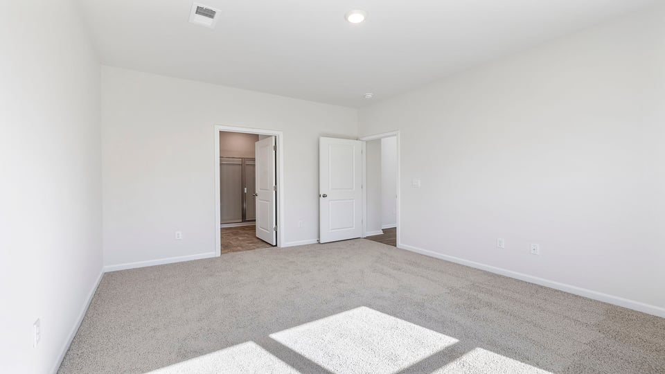 Primary bedroom with window and carpet.