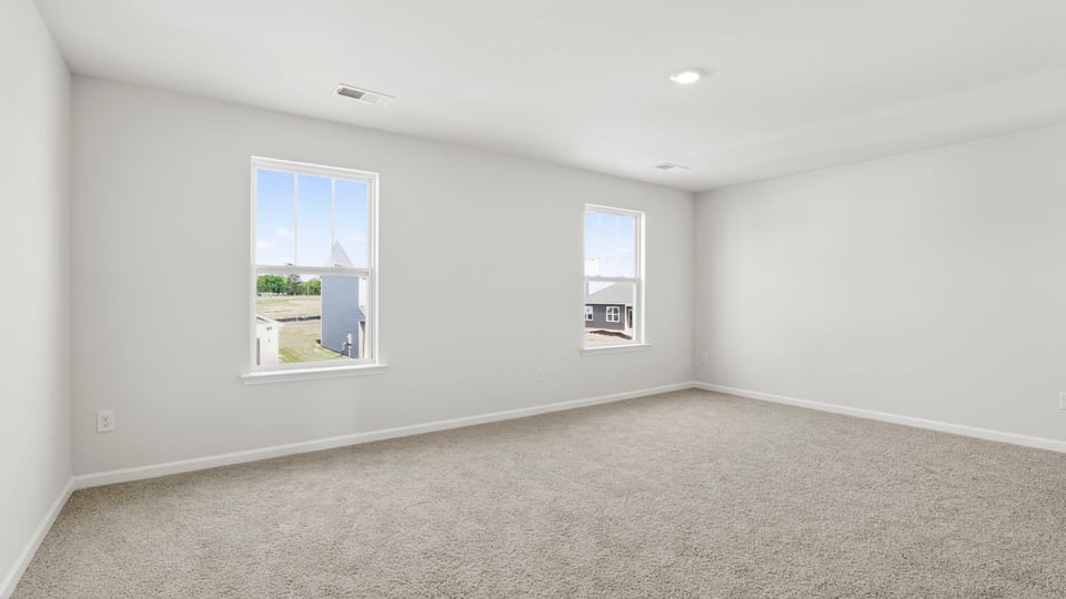 Primary bedroom with carpet and windows.
