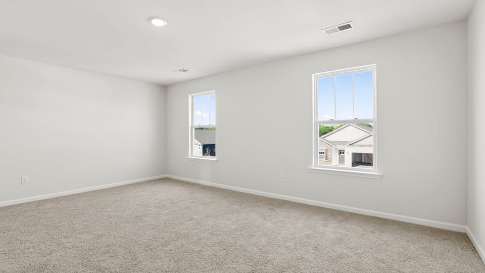Primary bedroom with carpet and windows.