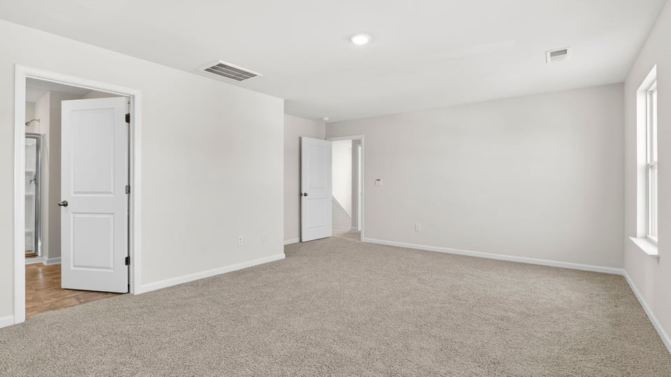Primary bedroom with carpet and windows.