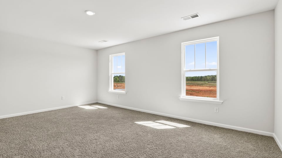 Primary bedroom with carpet and window.