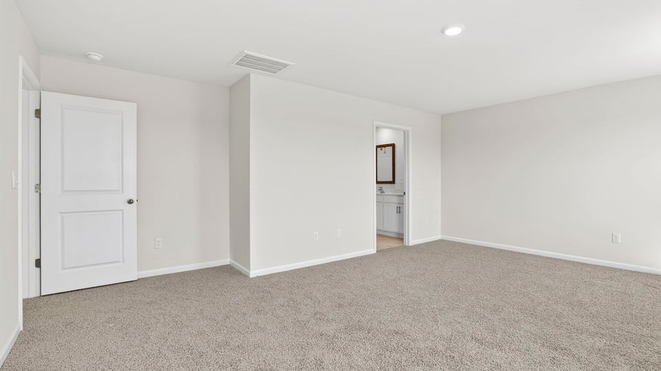 Primary bedroom with carpet and window.