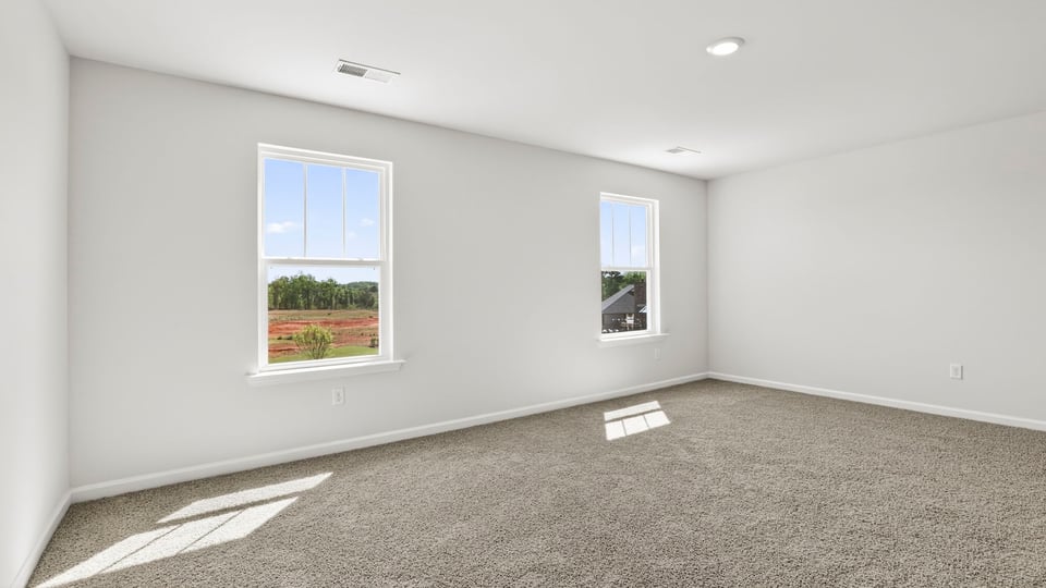 Primary bedroom with carpet and window.