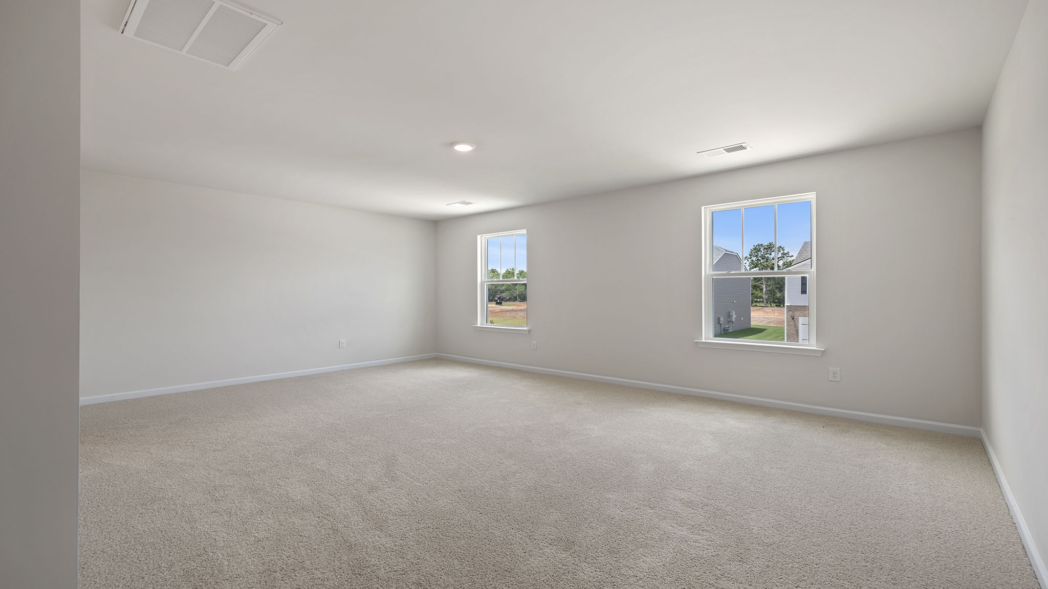Primary bedroom with recessed lighting and two large windows.