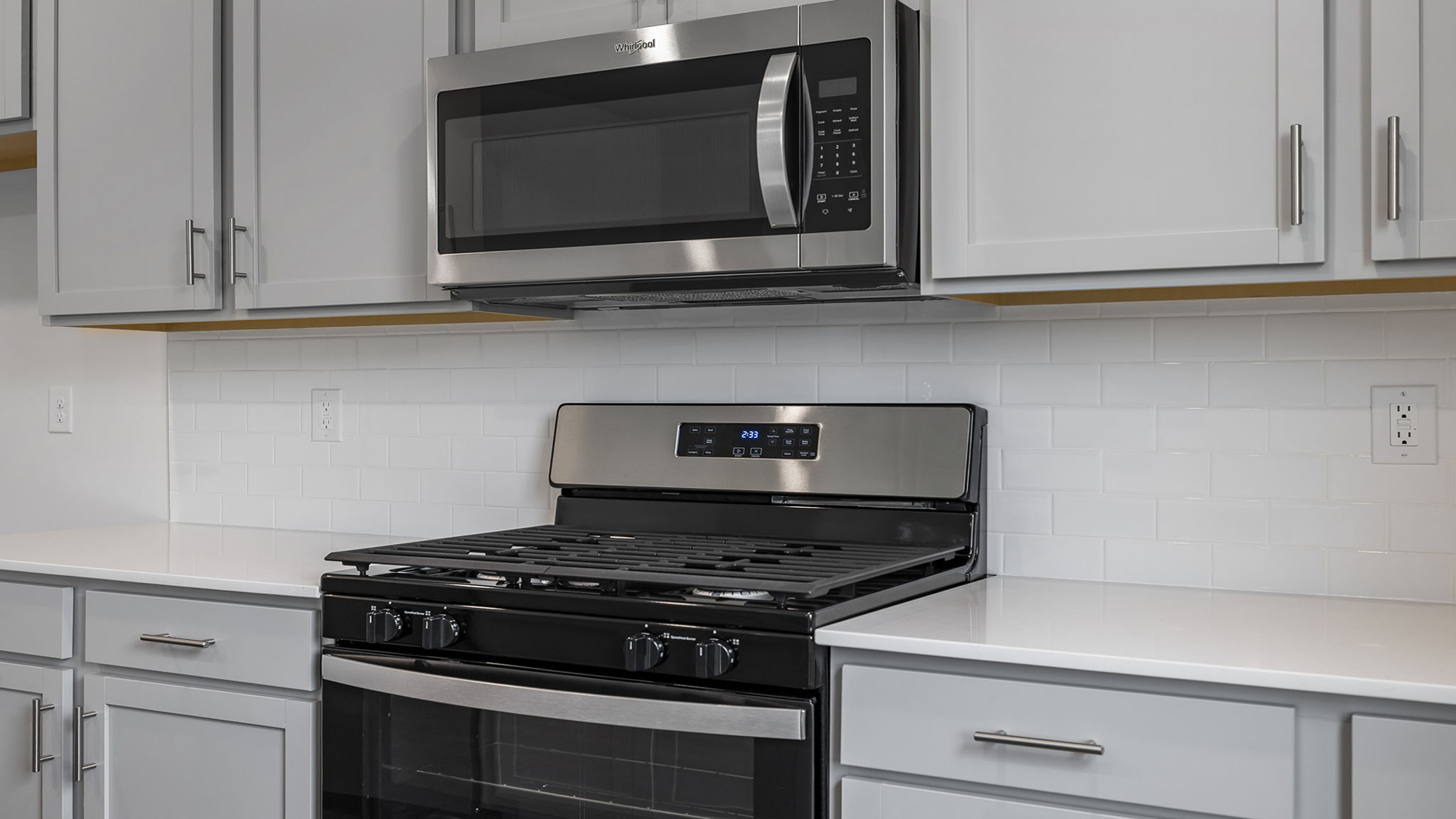 Close up look at cabinetry, quartz counterspace and stainless appliances