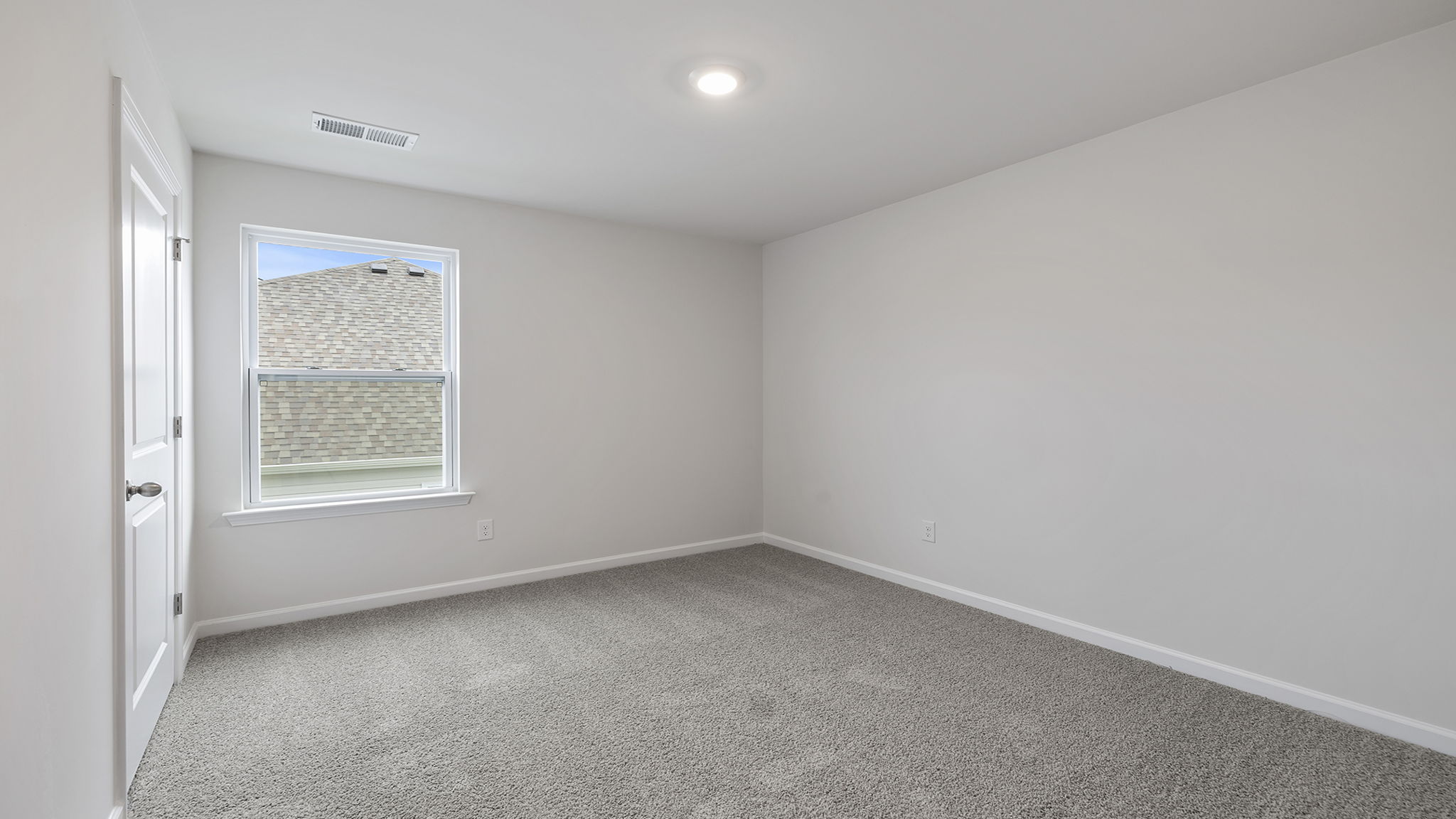 Bedroom with large window and carpet.