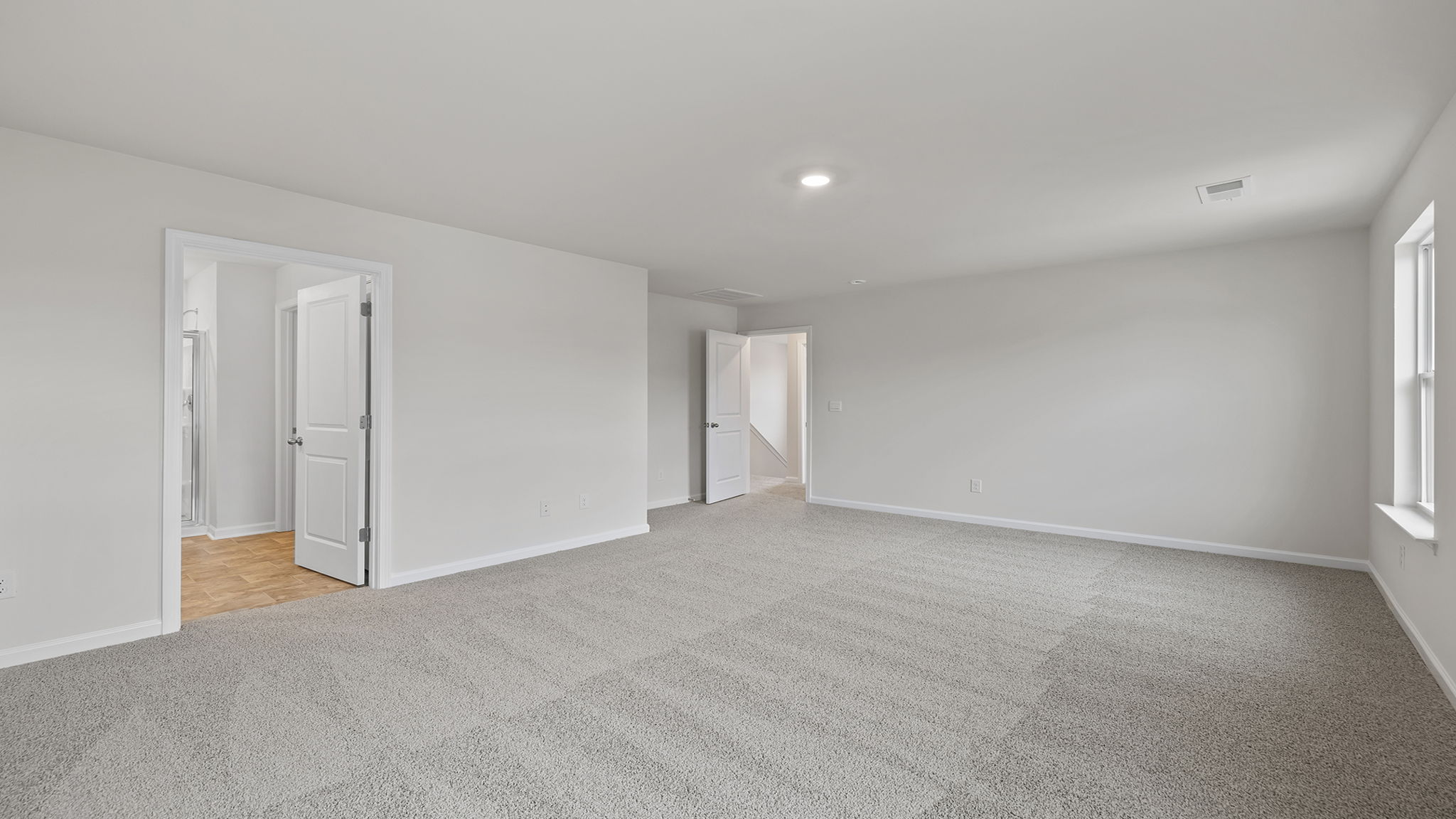 Primary bedroom with recessed lighting and carpet.
