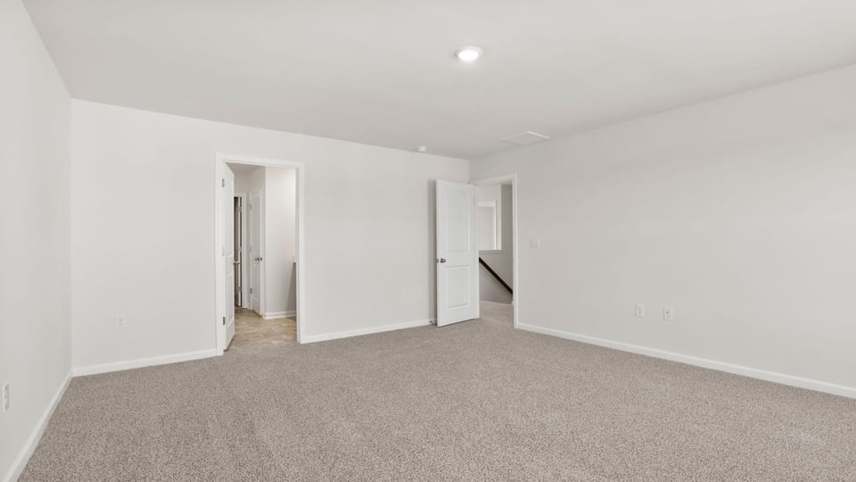 Primary bedroom with carpet and windows.