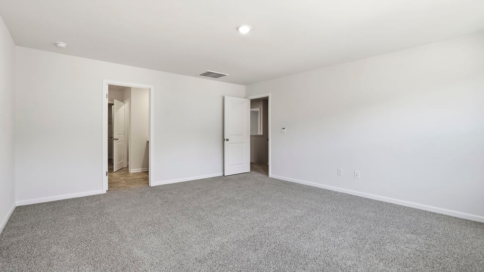 Primary bedroom with window and carpet.