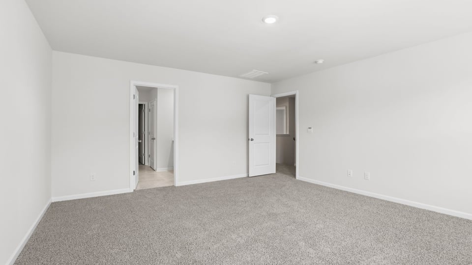 Primary bedroom with carpet and windows.