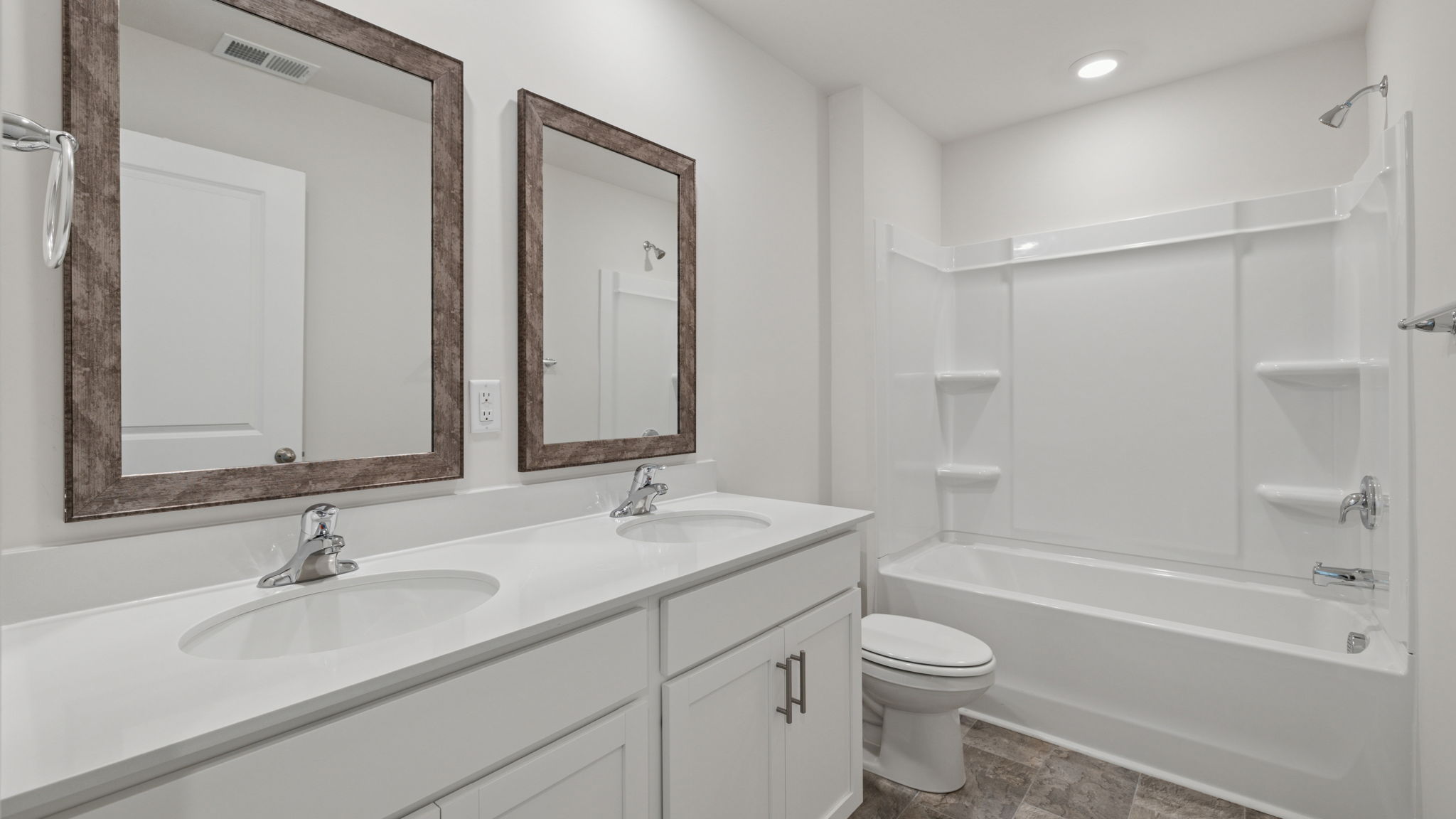 Hall bathroom with dual sink vanity and combination shower / tub.