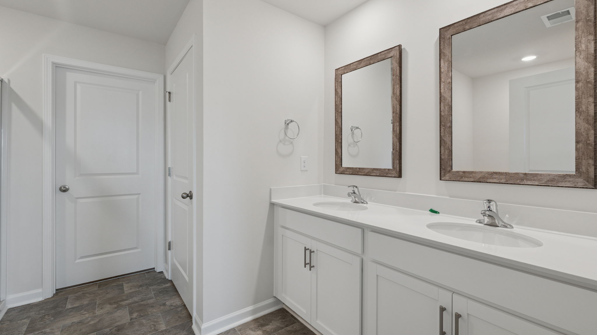Primary bathroom with double sink vanity with dual mirrors.
