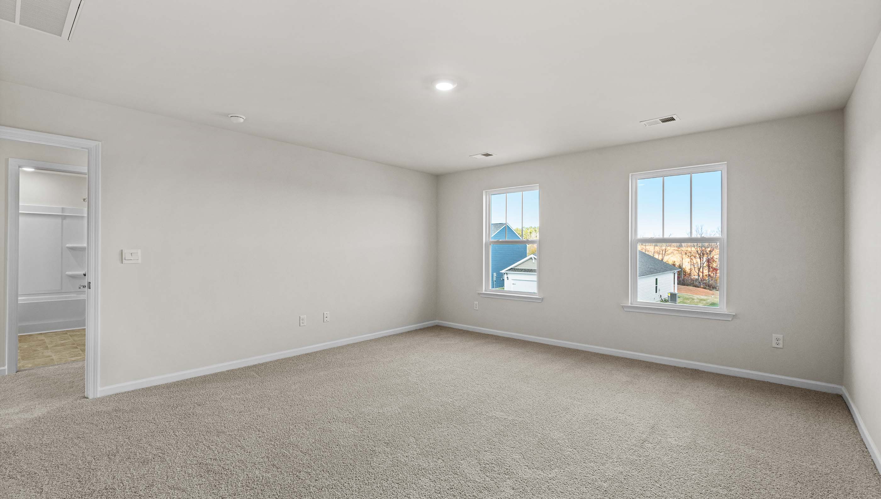 Primary bedroom with windows and carpet.