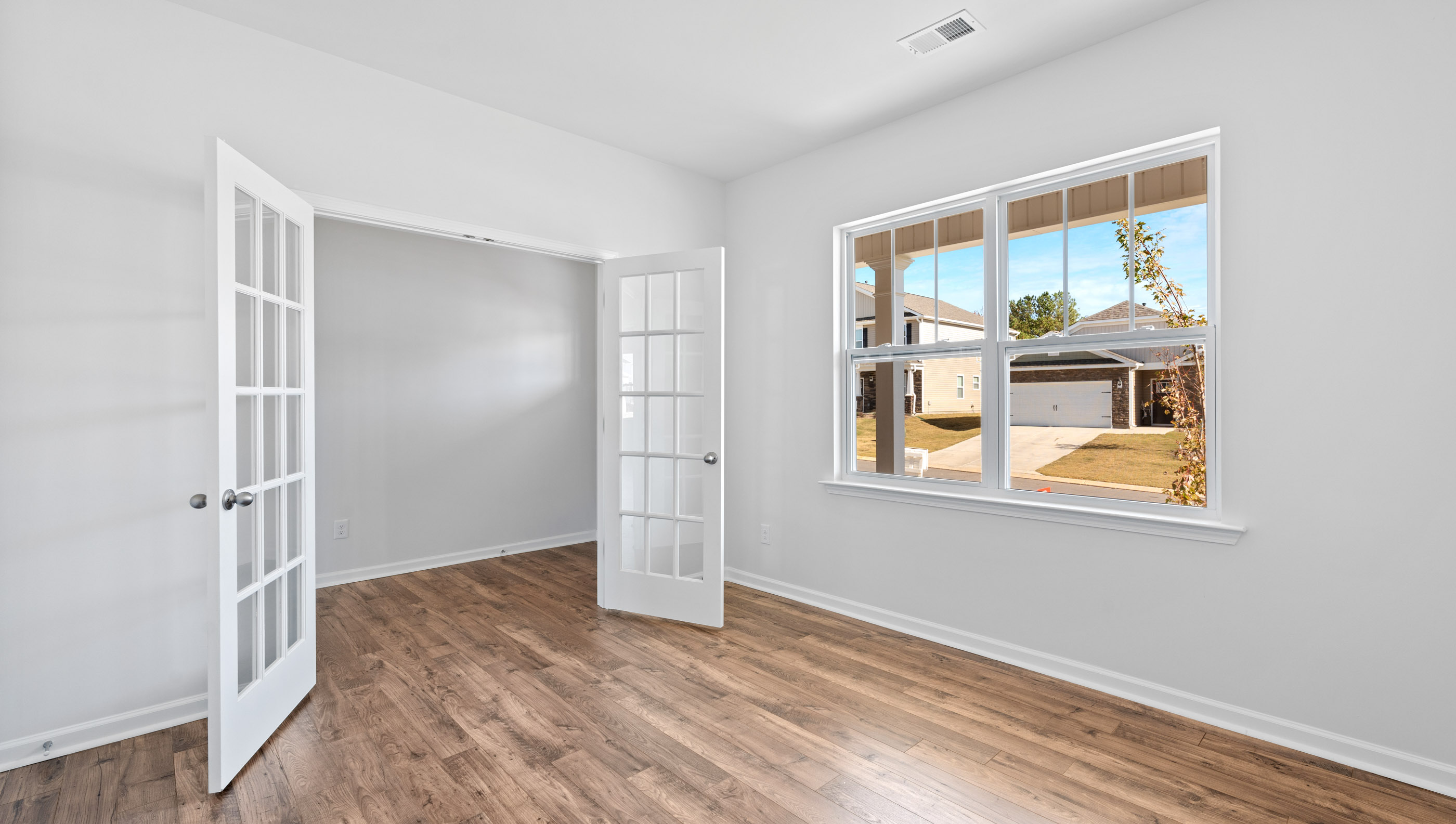 Study at front of home with large window and accented by French doors.