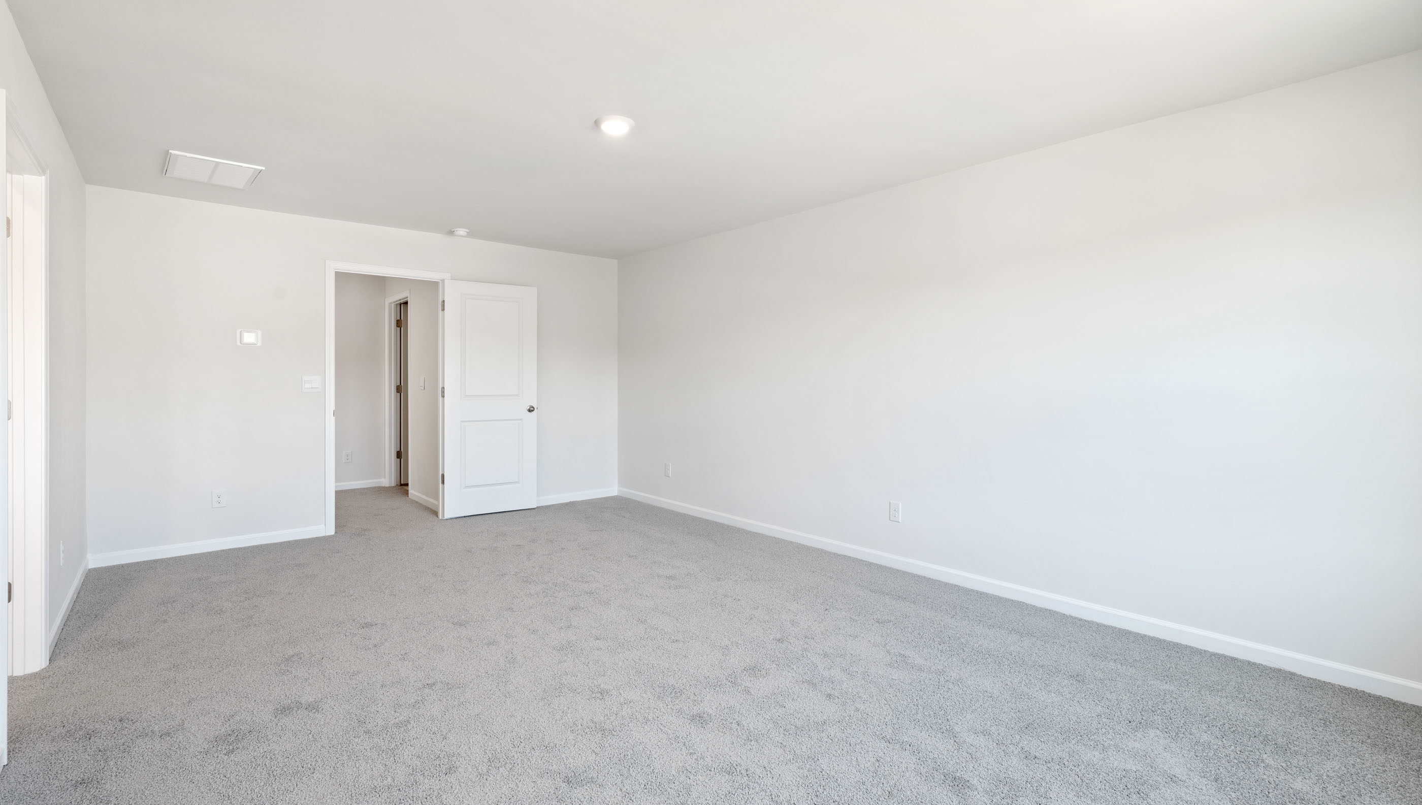 Primary bedroom with windows and carpet.