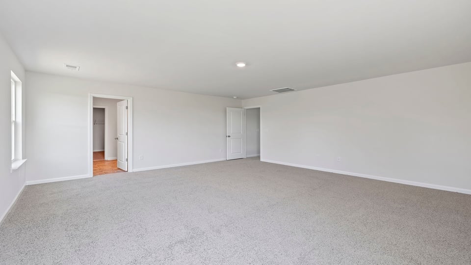 Primary bedroom with carpet and windows.