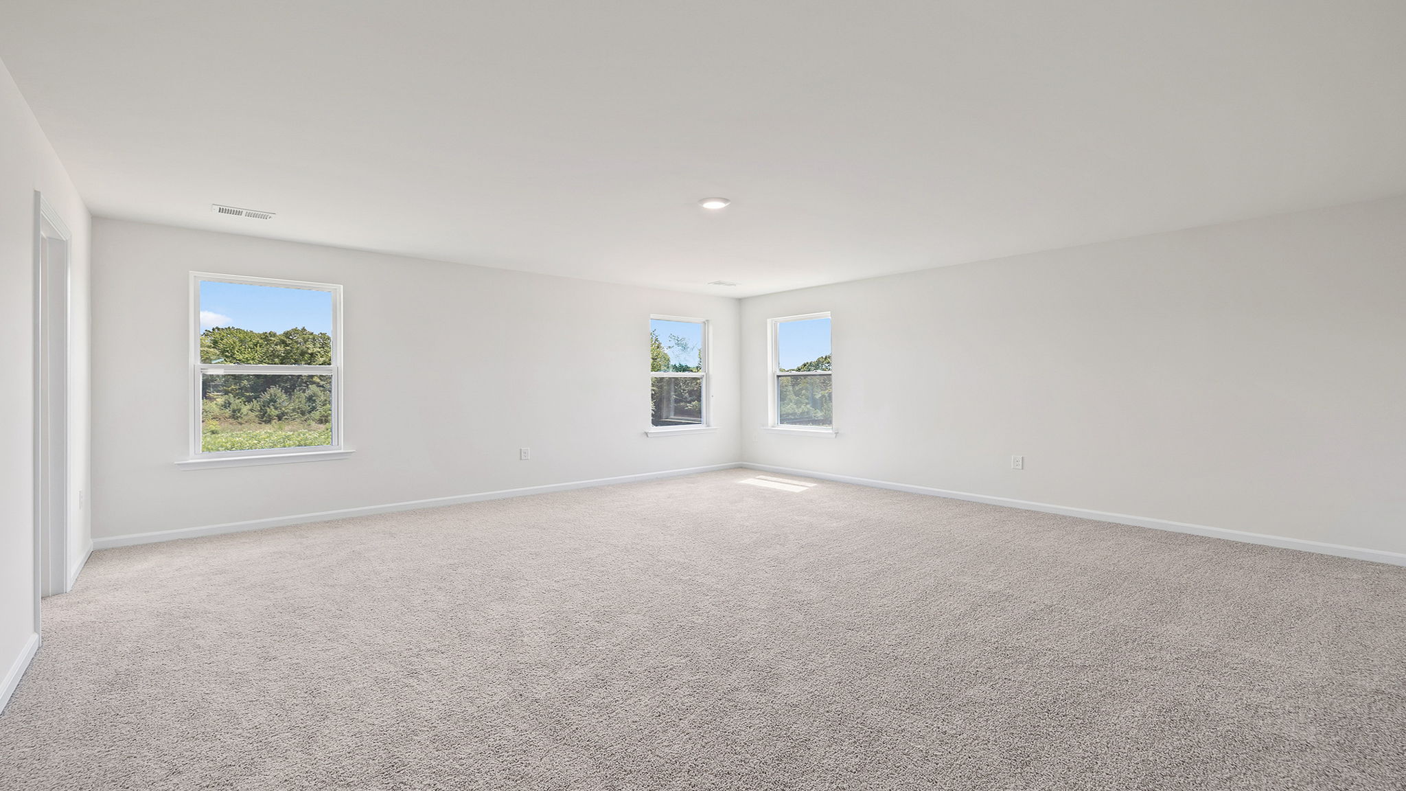 Primary bedroom with carpet and windows.