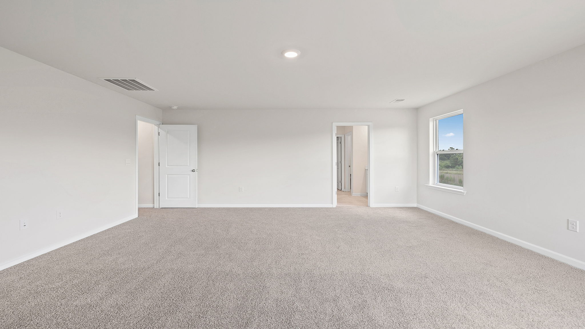 Primary bedroom with carpet and windows.