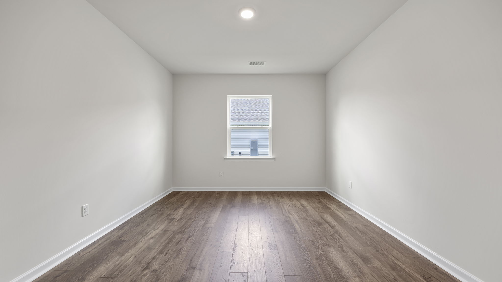 Formal dining room with window and laminate flooring.