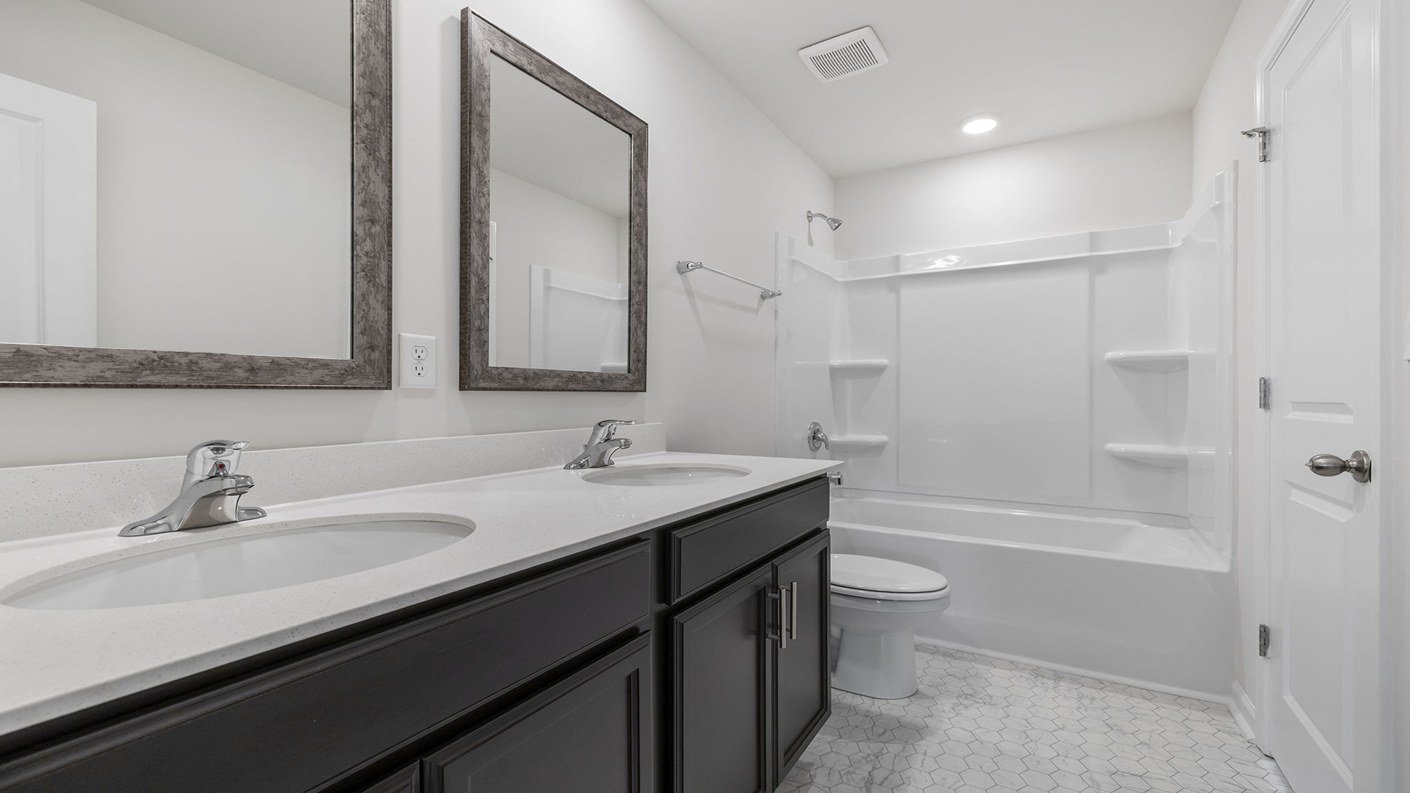 Hall bathroom with dual sink vanity and combination shower / tub.