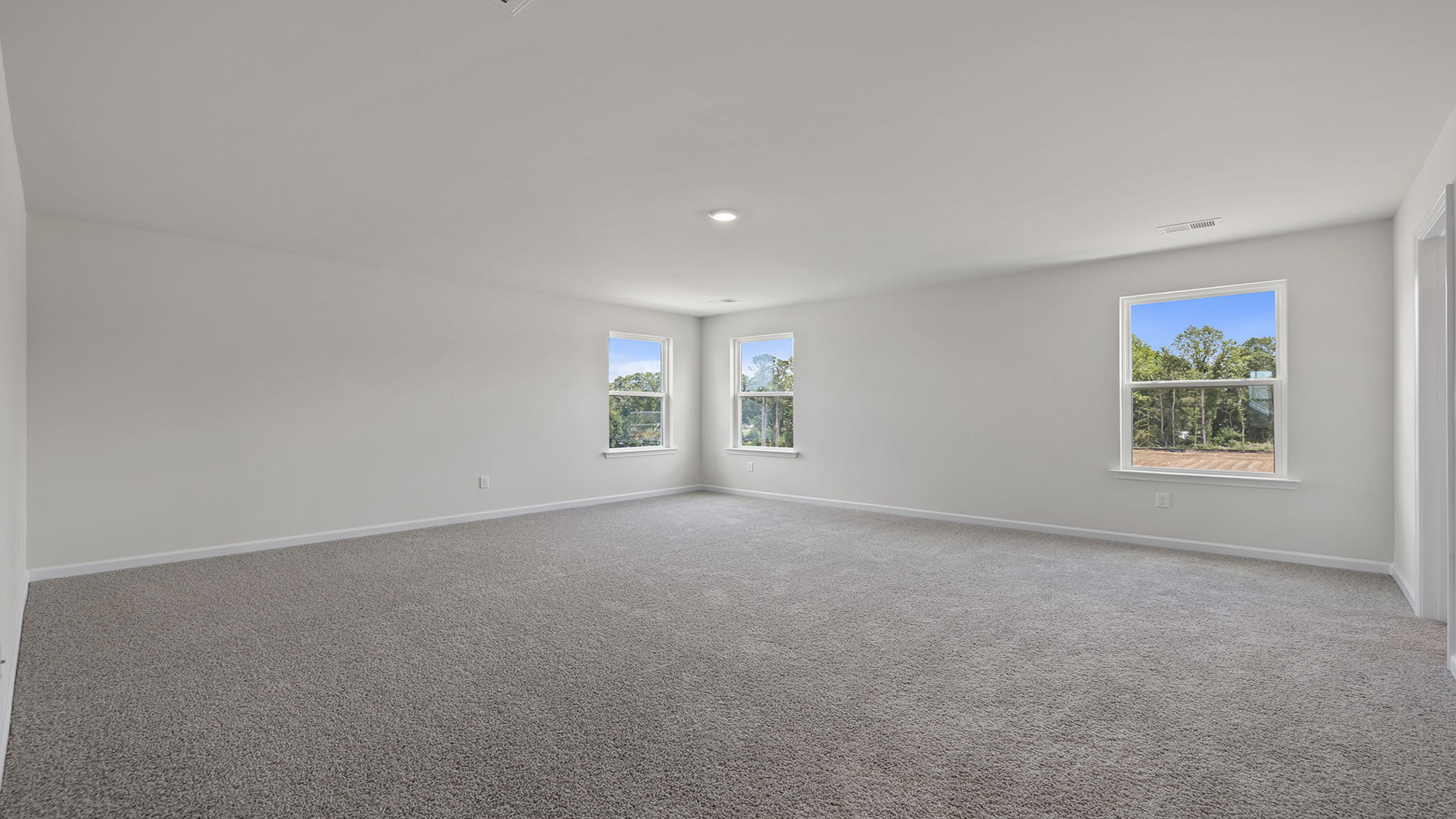 Primary bedroom with lots of windows and carpet.