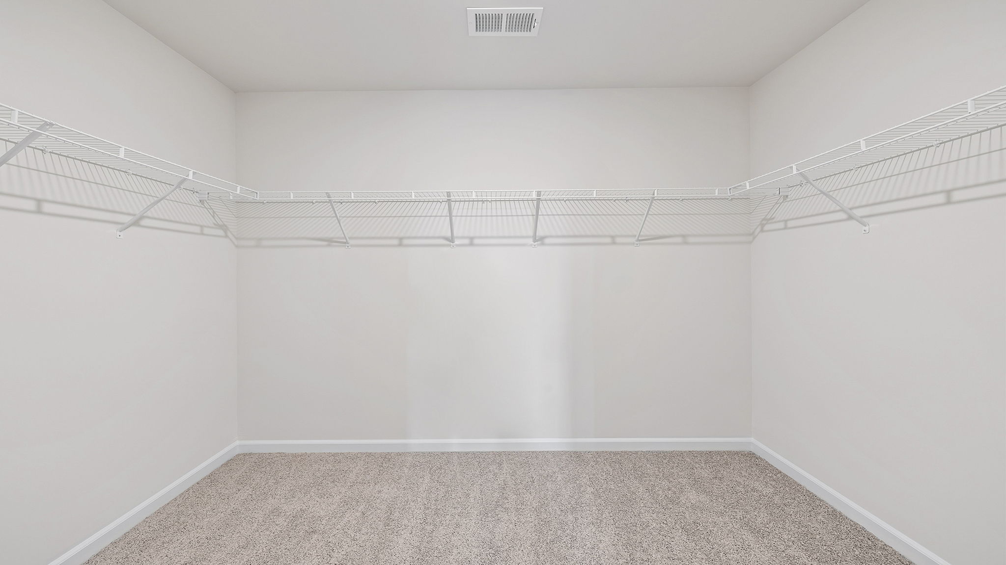 Primary closet with carpet and shelf.