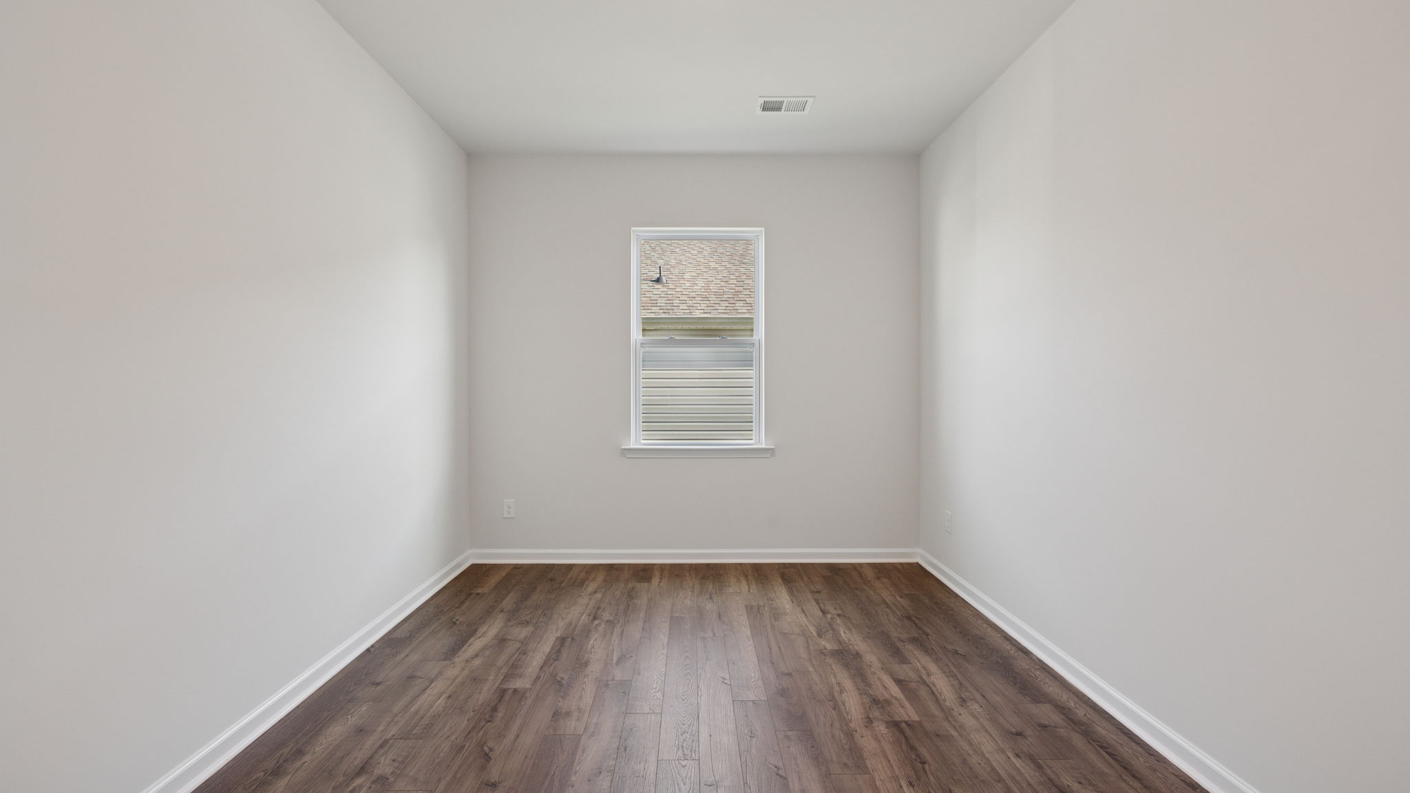 Formal dining room with window and laminate flooring.