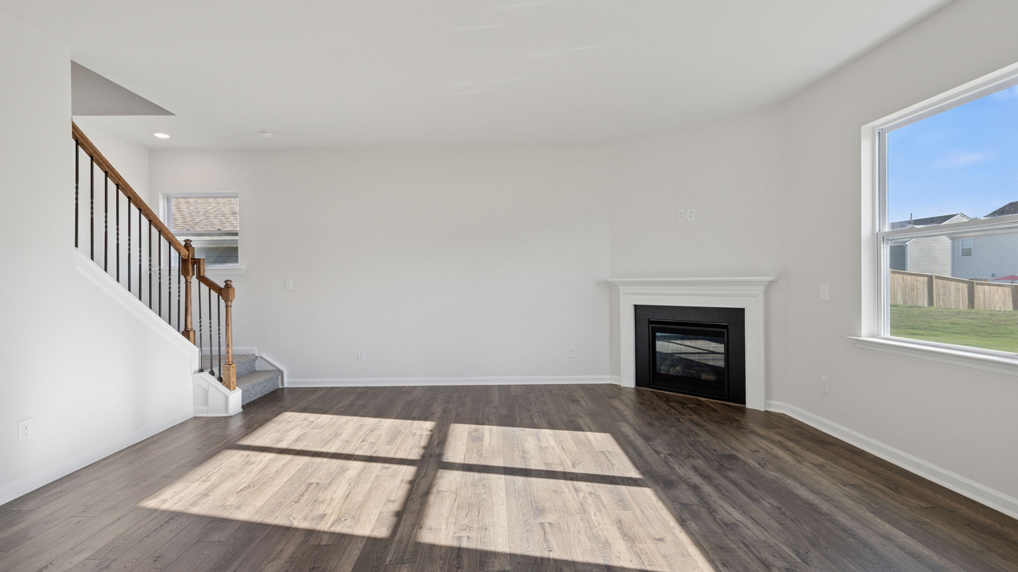 Family room with gas log fireplace and view of stairwell and hallway toward entrance.