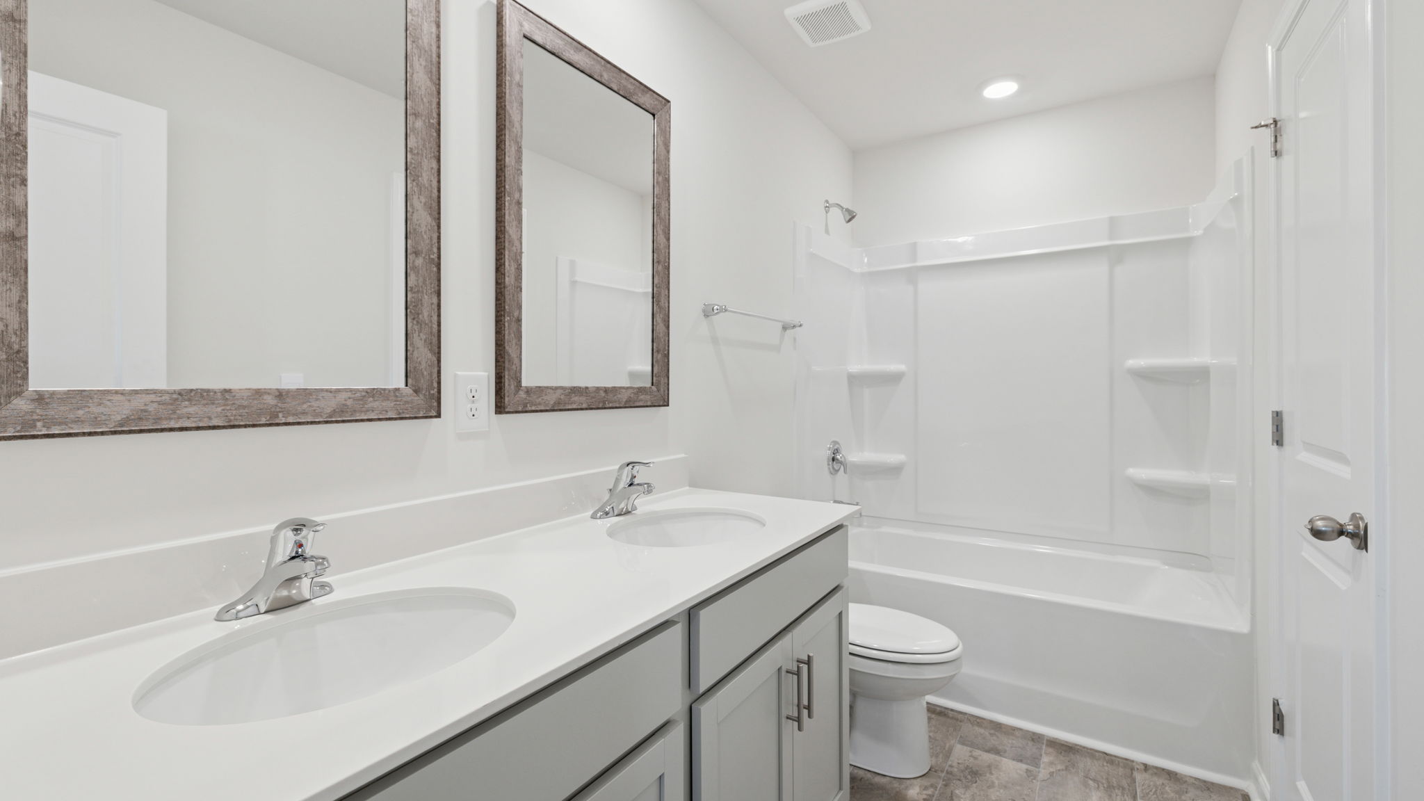 Hall bathroom with dual sink vanity and combination shower / tub.