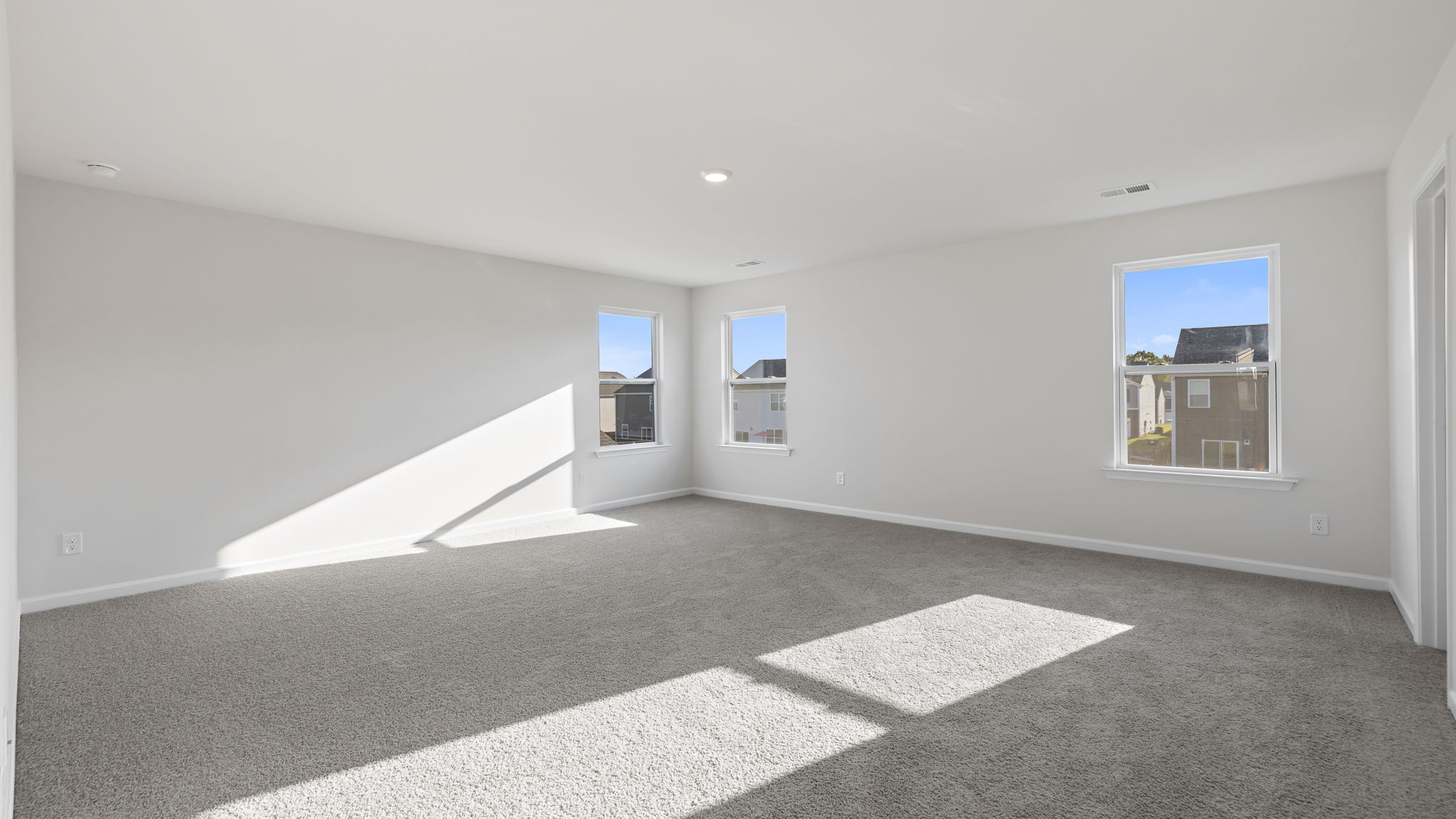 Primary bedroom with lots of windows and carpet.