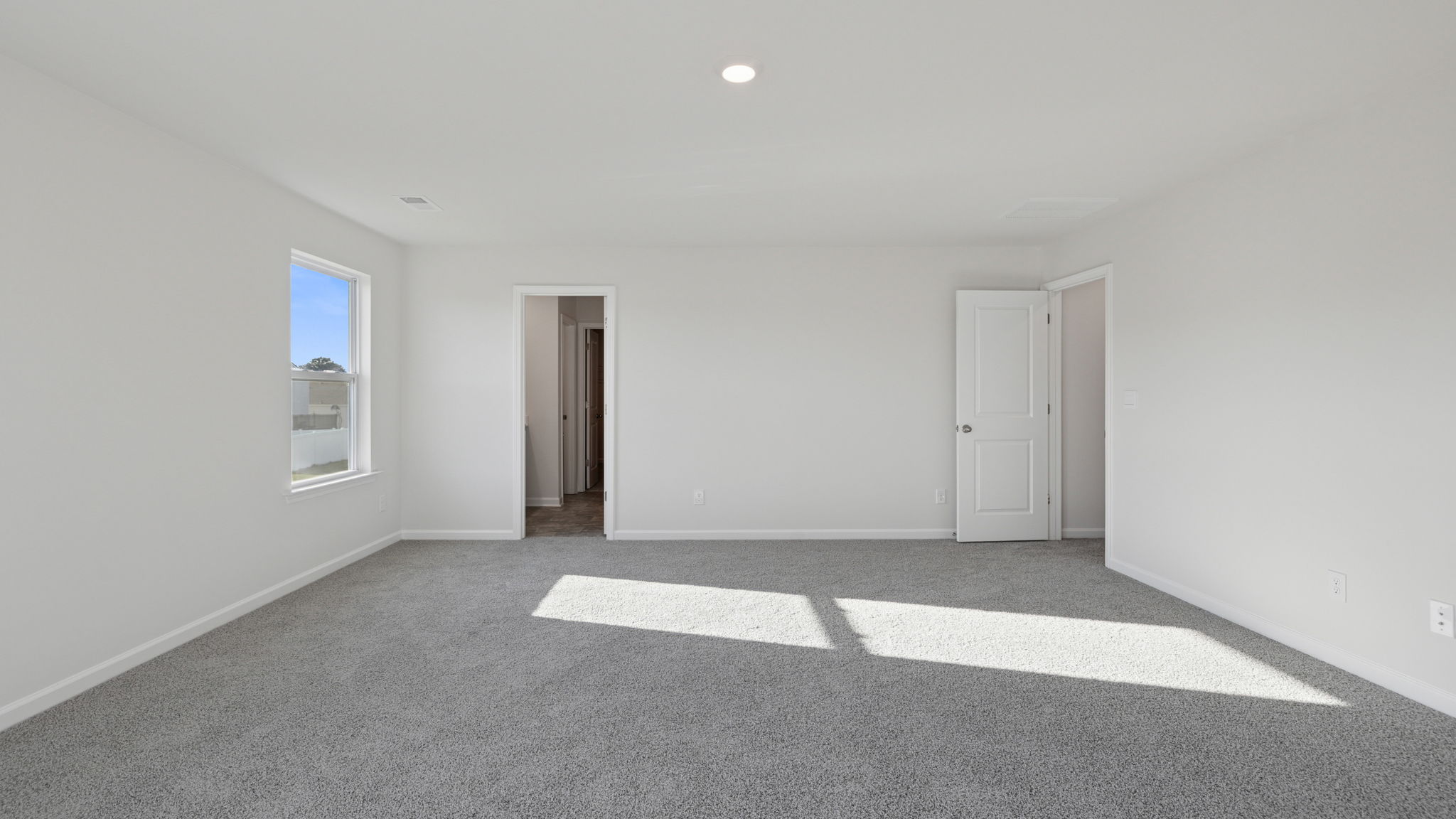 Primary bedroom with lots of windows and carpet.