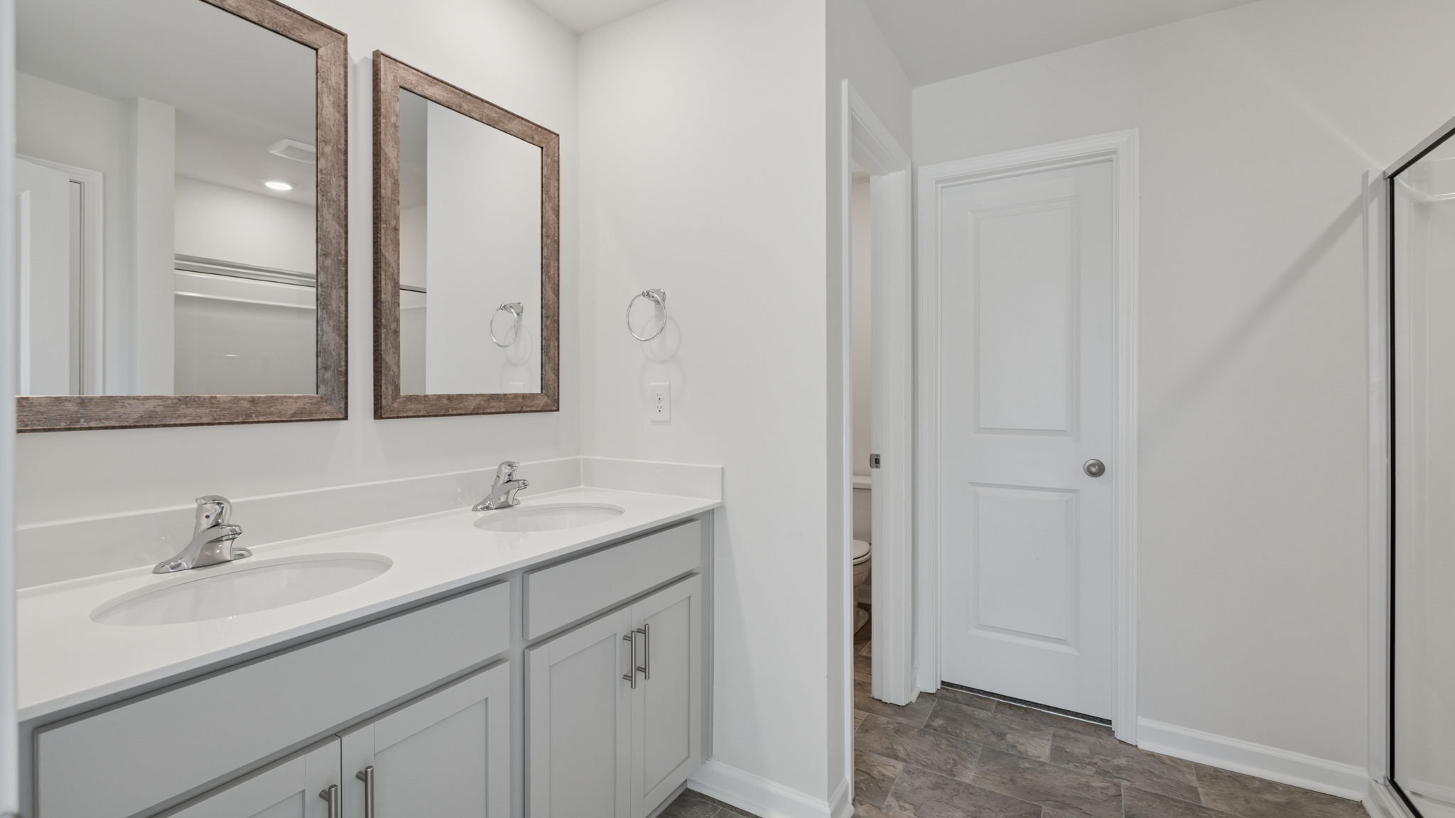 Primary bathroom with dual sink vanity and mirrors.