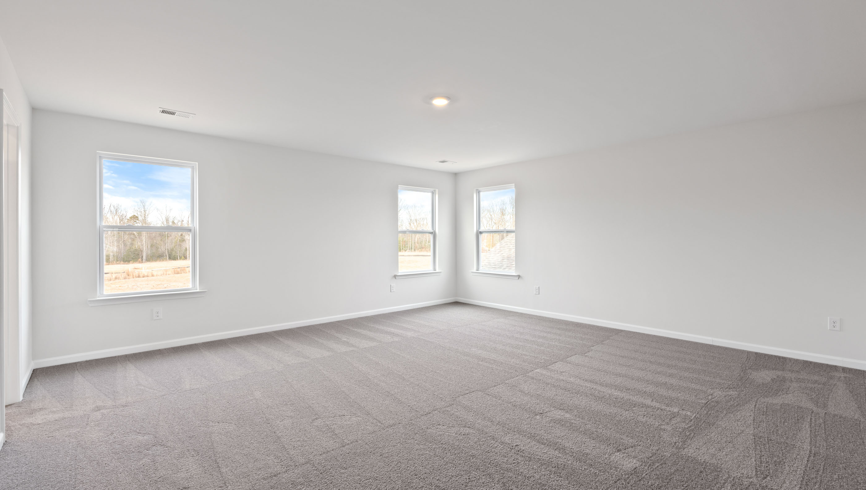 Primary bedroom with windows and carpet.