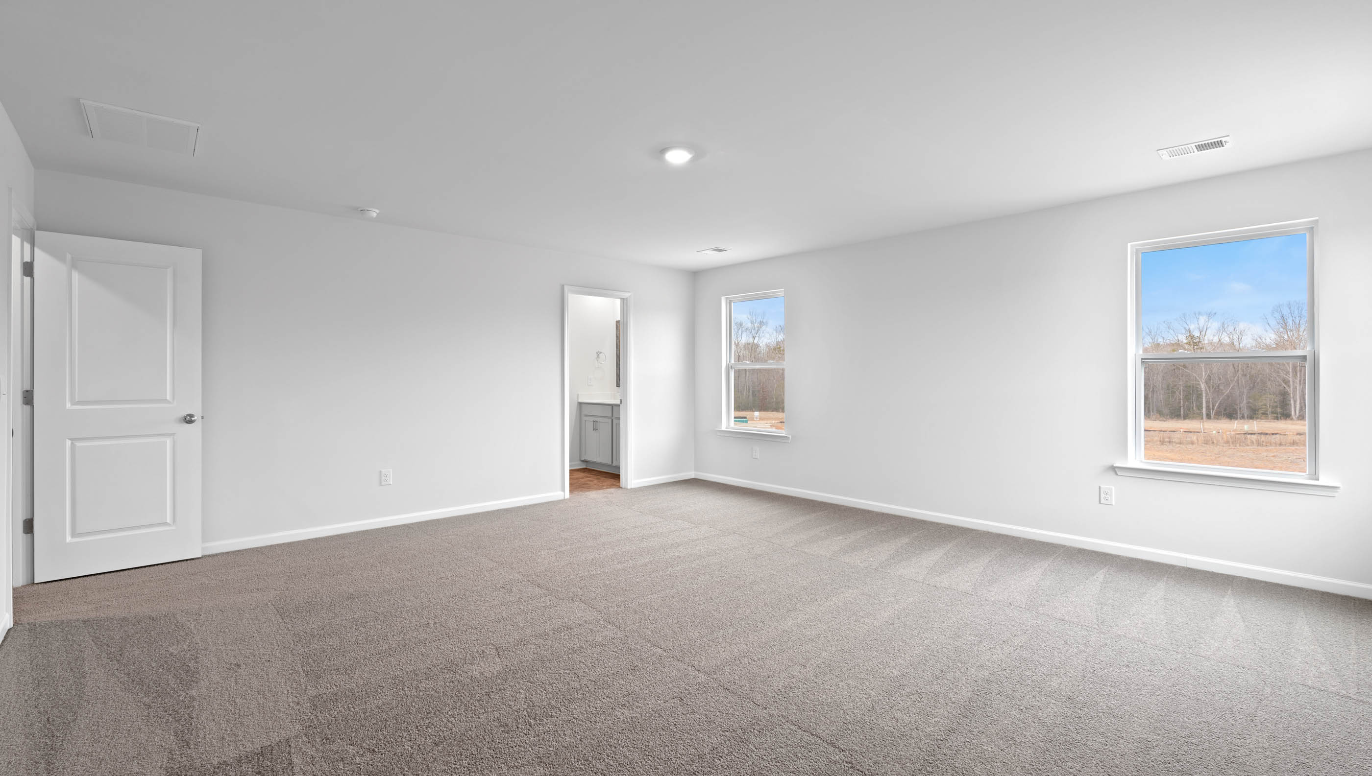 Primary bedroom with windows and carpet.