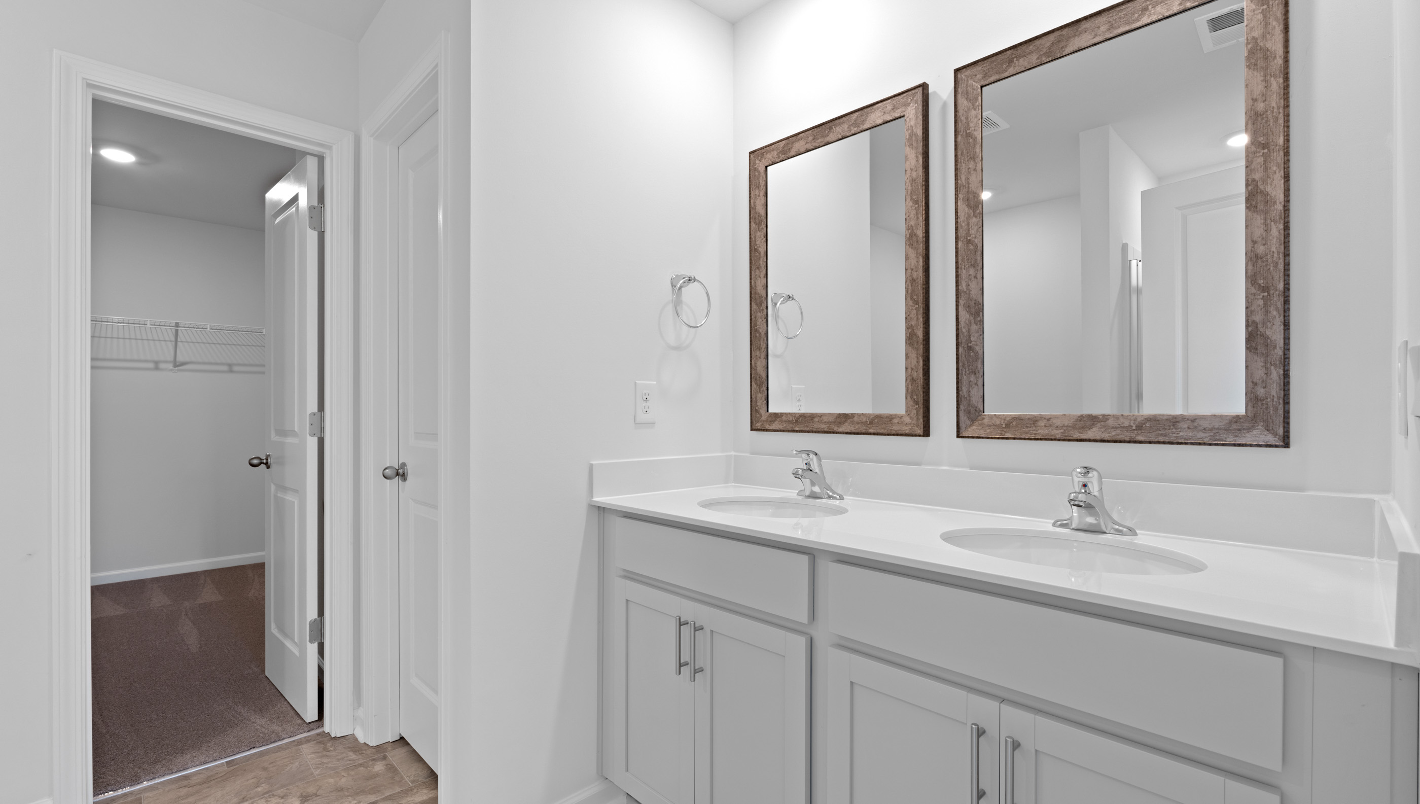 Primary bathroom with dual sink vanity and mirrors.