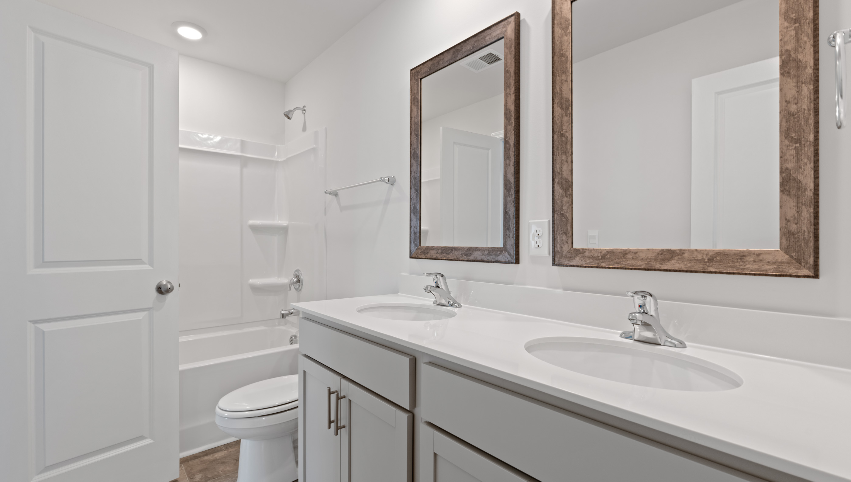 Hall bathroom with dual sink vanity and combination shower / tub.