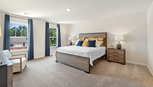 Primary bedroom with carpet and windows.