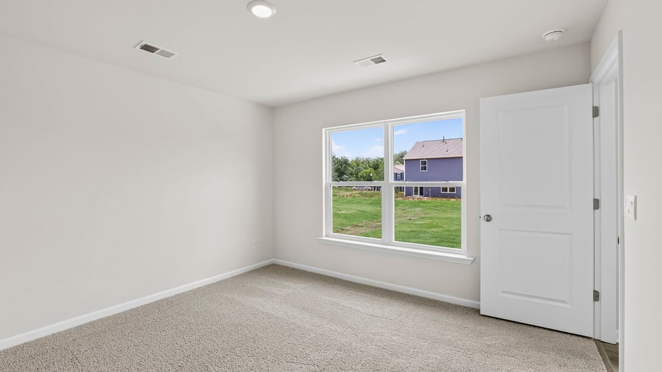 Primary bedroom with large window and carpet.