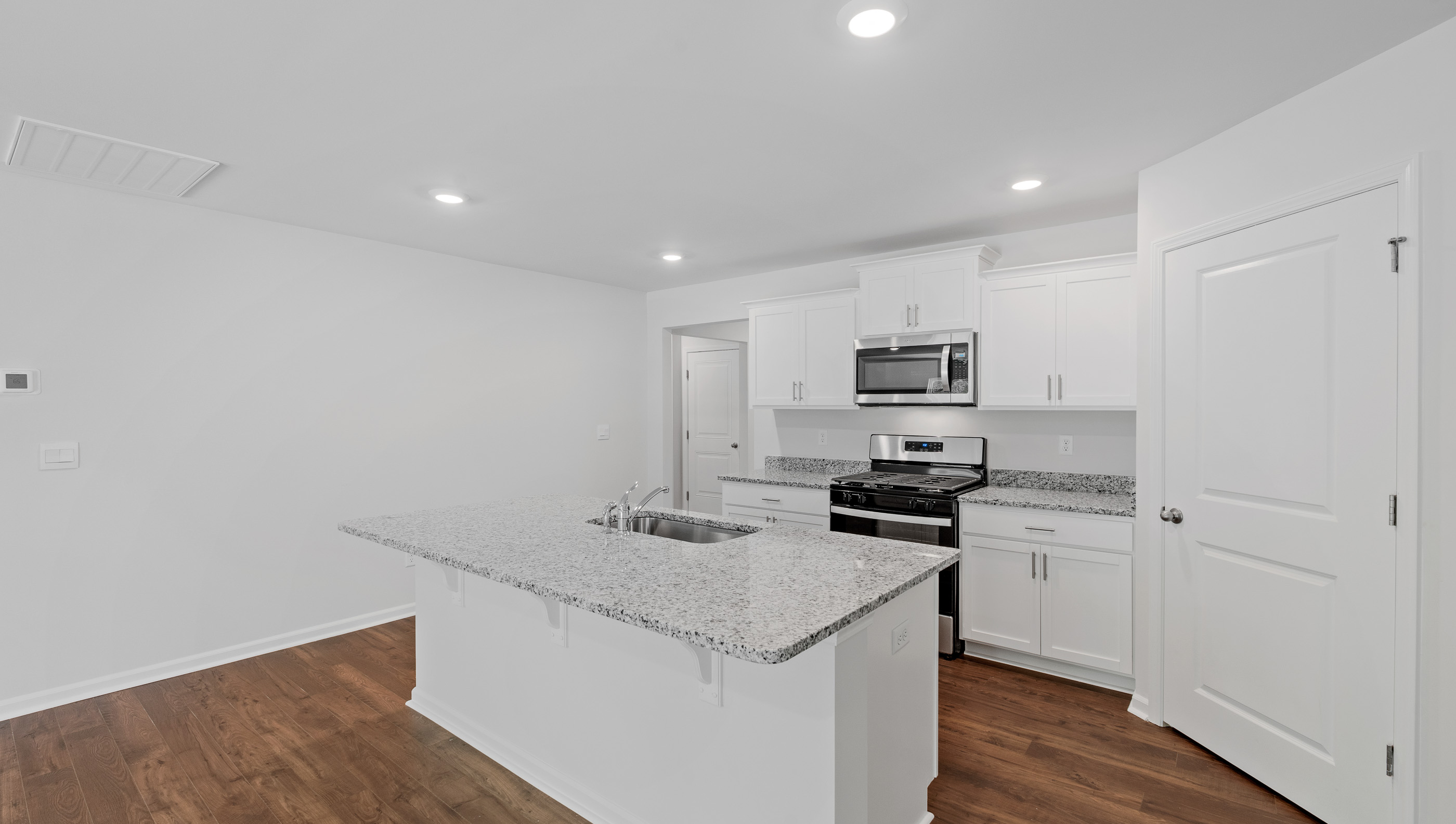 Kitchen and island with quartz countertops and  stainless steel appliances.
