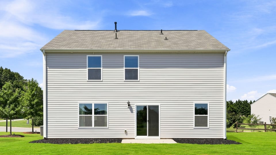 Back exterior of home with large yard.