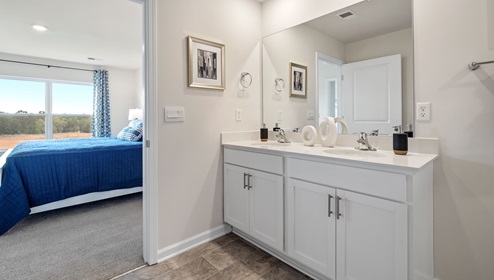 Primary bathroom with double vanity sink and view of bedroom.