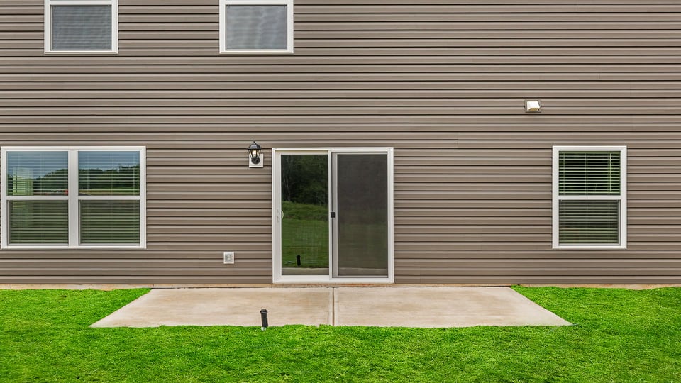 Bak exterior of home with small patio.