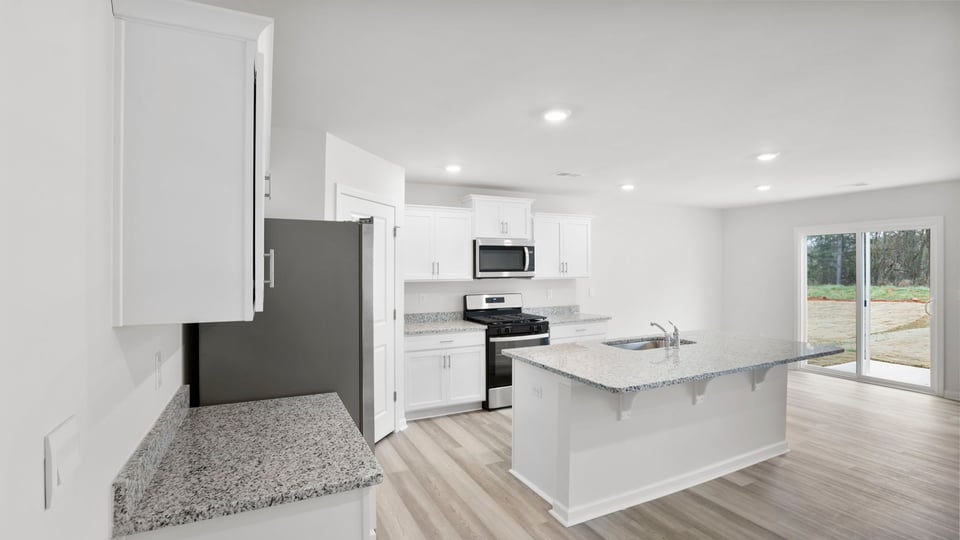 Kitchen area with granite island and stainless-steel appliances.