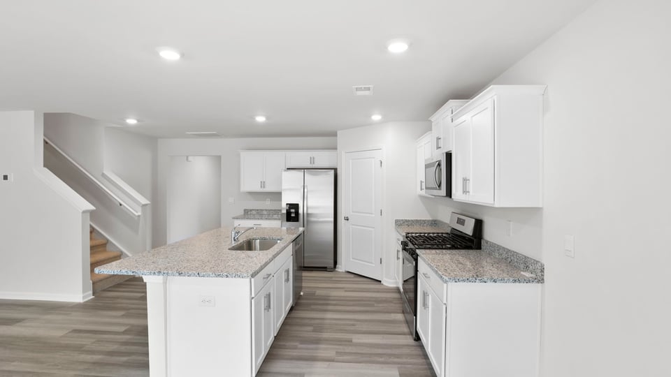 Kitchen area with granite island and stainless-steel appliances.