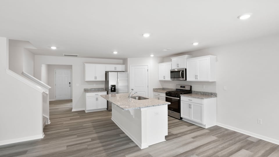 Kitchen area with granite island and stainless-steel appliances.