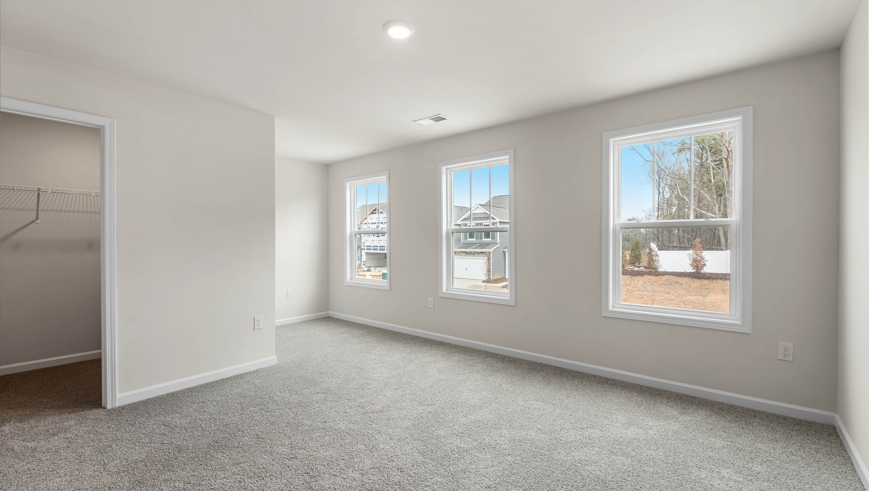Primary bedroom with carpet and window.