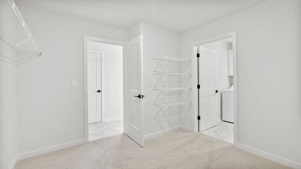 Walk in closet with door to laundry room.