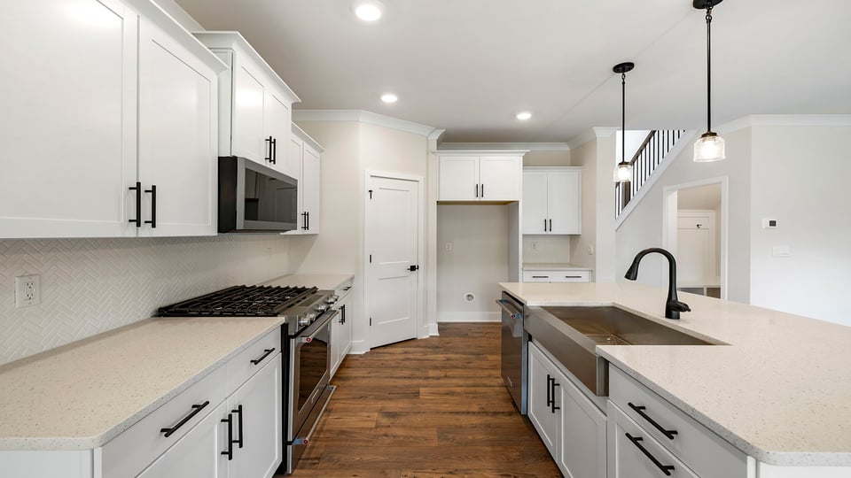 View of the kitchen island and granite countertops with stainless steel sink and dishwasher.