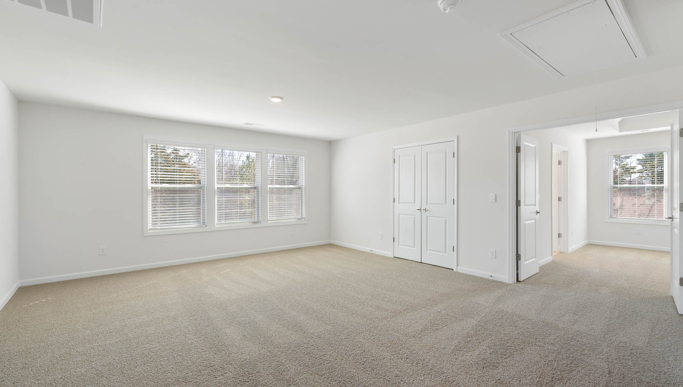 View of upstairs loft area with large windows, closet and open to upstairs bedroom.